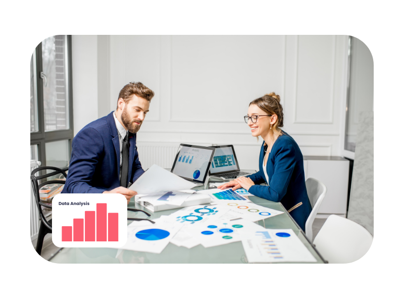 Two professionals analysing charts and data in a modern office, surrounded by digital reports—illustrating hands-on learning in a digital marketing apprenticeships.