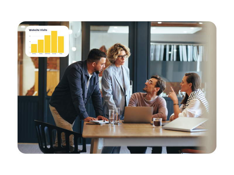 Group of professionals collaborating around a laptop in a modern office, with a website visits chart overlay, representing teamwork and real-world training in the multi-channel marketer apprenticeship.